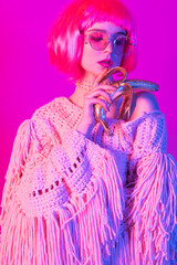 beautiful young woman with pink hair and golden banana glasses posing in spectacular neon style in colorful blue and pink light. futuristic concept 