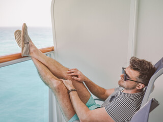 Fashionable man on the empty deck of a cruise liner against the backdrop of sea waves. Closeup,...