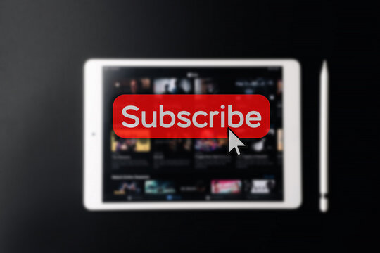 Subscription plan. Red online video subscribe button. Internet service on laptop digital tablet blured technology background. Visual contents concept. Social networking service.