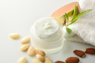 Moisturizing facial cream with almond extract on white table elevated
