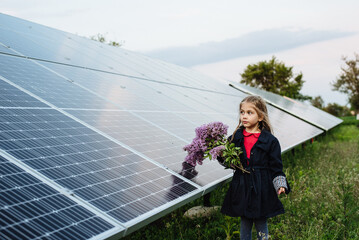 A child with a future of alternative energy and sustainable energy. The child holds flowers on a...