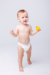 cute baby girl in a diaper playing with a rubber toy duck isolated on a white background