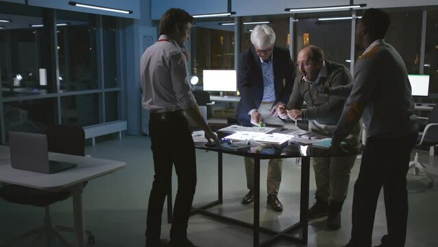 Multiethnic business team brainstorm and discuss late in dark office