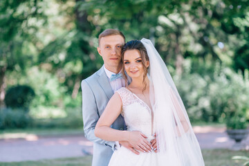 A young wedding couple is enjoying romantic moments on a summer green meadow.