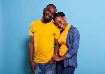 Obraz premium Portrait of young couple holding hands over blue background, showing love and gratitute for each other. Girlfriend and boyfriend expressing fondness and smiling, feeling happy in relationship.