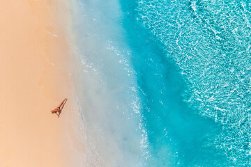 Aerial view of a girl on the beach on Maldives island. Vacation and adventure. Beach and turquoise water. Top view from drone at beach, azure sea and relax girl. Travel and relax concept, carefree