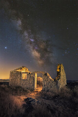 Vertical shot of an old abandoned broken ancient building in the background of a starry sky.