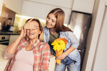 Teen daughter congratulates mom and gives her flowers.