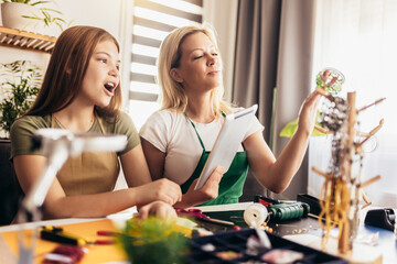 Mother and daughter accessories designers making handmade jewelry in studio workshop. Fashion,...
