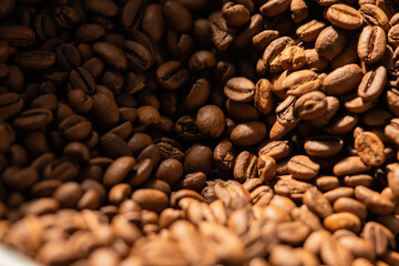 Production of freshly roasted coffee beans. Roasting process in an industrial coffee roasting machine in a factory. Mixing roasted coffee beans. Food and drink background for cafe.