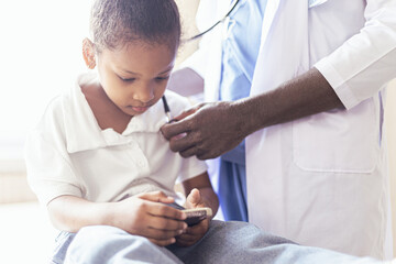 African male pediatrician holding a stethoscope, child, patient, goes to the doctor , checks the lungs, the heart of the child, does the child's examination in the children's hospital