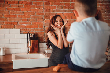 a beautiful pregnant mother plays with son in the kitchen. a happy family. 