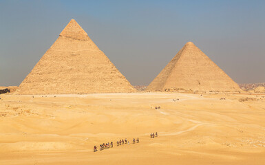 The great Pyramid complex of Giza with tourists riding camels in front of the Egyptian pyramids. Cairo, Egypt