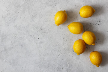 Yellow lemons on the gray background. Top view flatlay with the copyspace.
