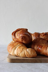 French croissants on the wooden board, on the grey background with copyspace.