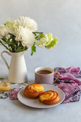 Fototapeta na wymiar Sweet buns on a plate. Flowers in a vase and a cup of tea. Photo