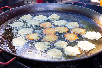 Potato fritters fried in a large frying pan