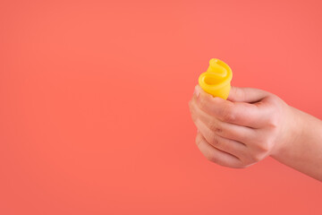 Close up view of woman holding yellow menstrual cup isolated over pink background, woman's period, menstrual cup in hands, modern methods for crytical days. Gynecology and hygiene products concept
