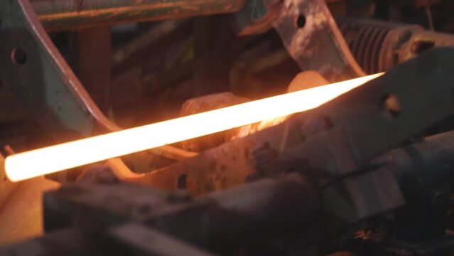 Rolling metal in production, moving on a hot metal ribbon, ball production phase, production process at a metal rolling plant, rolling through sparkling metal rollers