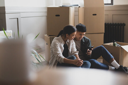 Mid adult couple sitting on the floor of their new home surrounded by boxes