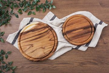 Wooden board, food plates on linen kitchen towel on dark wood table