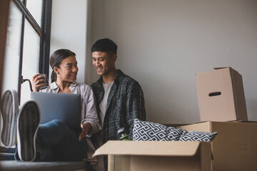 Mid adult couple moving house and using a laptop