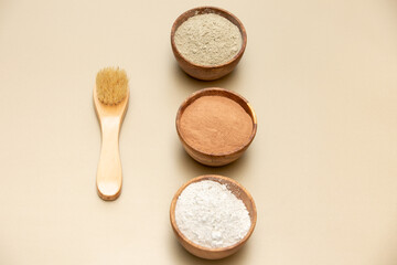 Organic green, red, white face mask clay in wooden bowls with bamboo and goat hair brush on beige background. Home skin care concept.Self care