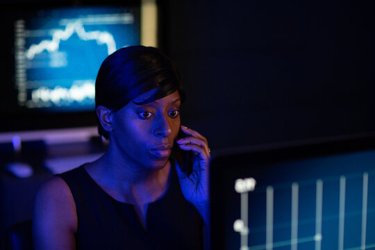 Female stockbroker trading late at night using smartphone