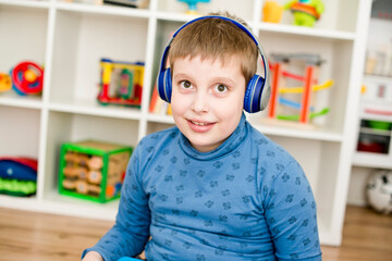 blue dressed kid with blue bluetooth wireless headphones. big eyes with a shy smile