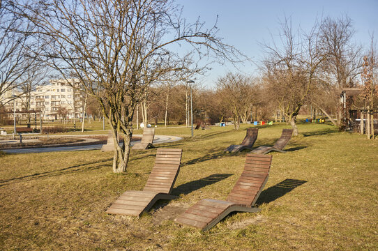 Beautiful View Of Two Wooden Empty Seats On Green Grass In The Rataje Park On A Sunny Day