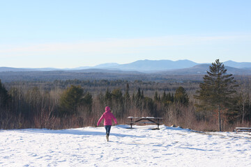 Back view of a person in a pink jacket on the snowy Robbins Hill scenic overlook in Maine