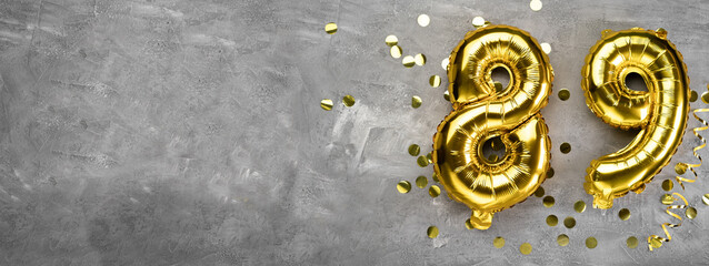 Yellow foil balloon number, number eighty nine on a concrete background. Greeting card with the inscription 89. Anniversary concept. for anniversary, birthday, new year celebration. banner,
