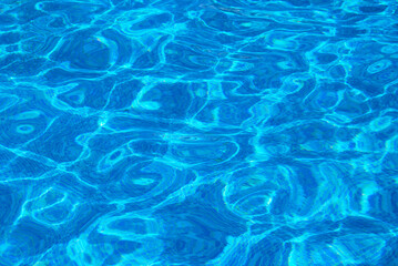 Clear water surface, ripple water in tiled swimming pool with sun reflection