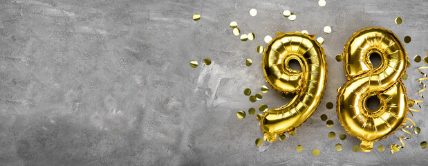 Yellow foil balloon number, number ninety-eight on a concrete background. Greeting card with the inscription 98. Anniversary concept. for anniversary, birthday, new year celebration. banner,