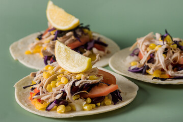 Homemade Shredded Chicken Tacos with Corn Tomatoes and Other Vegetables Green Background Horizontal