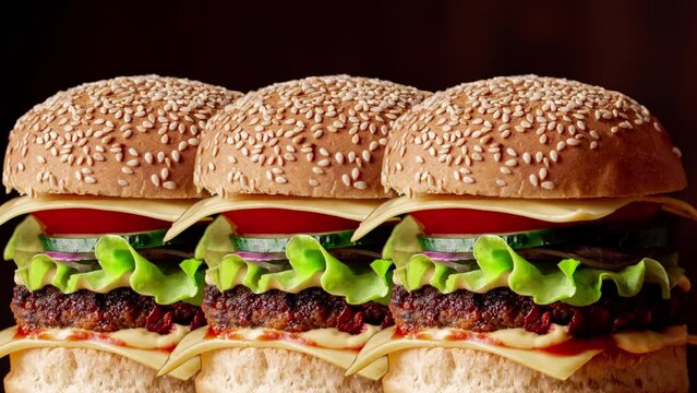 Hamburger day. Fresh tasty burgers appear and move. Dark background. Animation.