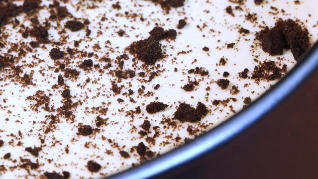 Close up view of homemade chocolate and cream cheese cake into a metal pot, rotating. Macro shot.
