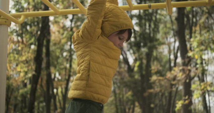 Boy having fun climbing on monkey bars at playground
