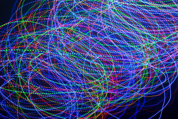 Glowing traces from the movement of LEDs in the dark. Light effect of spirals or circles in the dark. Abstract background or texture. Chaotic movement of light.