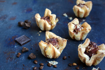 Closeup of puff pastries with dark chocolate chips and currant filling on a dark blue background. delicious desserts