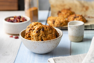 Healthy sugar-free oatmeal cookies with nuts, raisins, dried cranberries and cinnamon in a ceramic bowl on a colored wooden background.