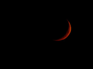 Closeup shot of a red crescent moon on a completely black sky