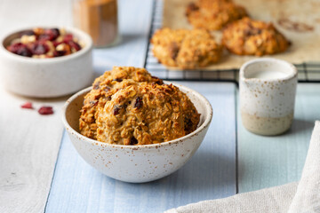 Diet cookies with oat flakes, nuts, raisins, dried cranberries, cinnamon, sugar-free in a ceramic bowl on a colored wooden background. Healthy baking concept