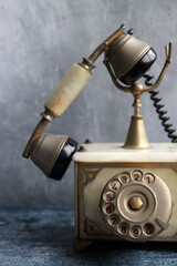 Old fashioned rotary phone on a table. Vintage telephone close up photo. Grey textured background with copy space.