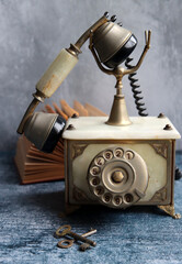 Old fashioned rotary phone on a table. Vintage telephone close up photo. Grey textured background...