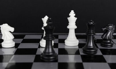 The king in a battle chess game stands on a chessboard with a black isolated background. Business Leadership Ideas.