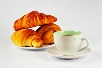 Yellow croissant in a plate and coffee isolated on a white background. Classic breakfast close up.