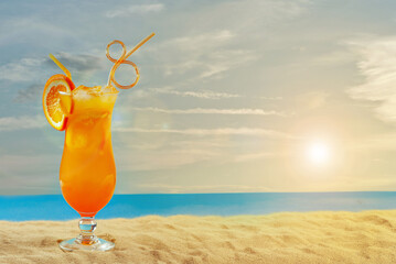 Orange cocktail on the beach. Alcoholic drink with ice, orange on the sand close up. Sunset, sea...