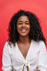 Mid waist portrait of african american empowered woman with happy expression. Vertical portrait of african cheerful woman in red background. Isolated people on background
