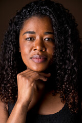 Cropped portrait of african american empowered woman with calm expression. Vertical closed up view of african woman with serene expression in brown background. People and emotions concept